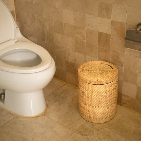 Woven rattan bin with rotating lid, front view in bathroom beside toilet