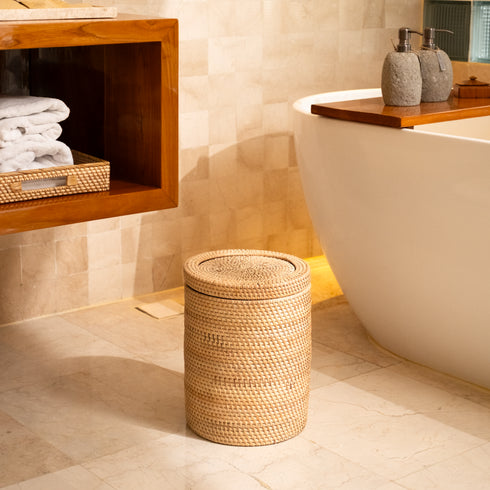 Woven rattan bin with rotating lid styled next to a freestanding bathtub