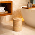 Woven rattan bin with rotating lid styled next to a freestanding bathtub