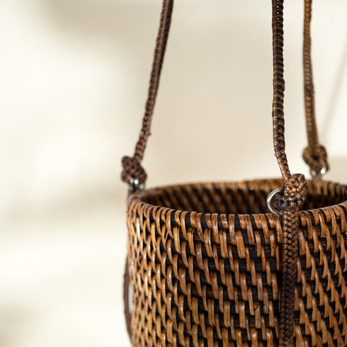 Close up of dark brown rattan hanging planter showing contrast weave and cord detail