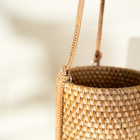 Handwoven rattan hanging planter close up showing natural weave detail and braided cord attachment