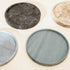 Four round marble trays of different colors on a light surface