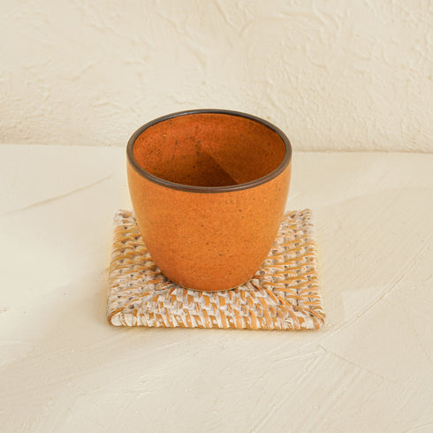 A Brown Ceramic Cup with White Rattan Square Coaster