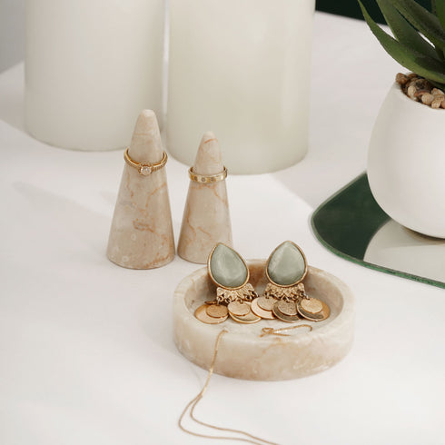 A table with a vase, marble ring holder, and a pair of earrings