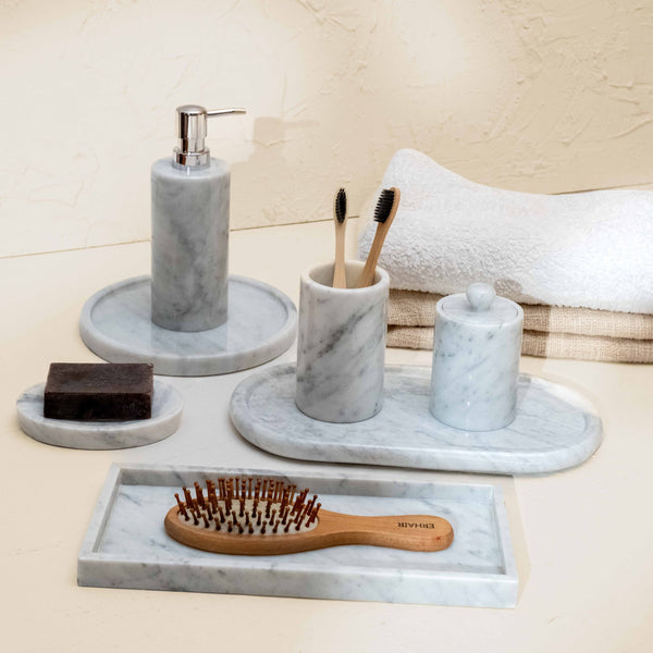 Bathroom set with marble tray, soap dispenser, toothbrush holder, and hairbrush on a neutral background