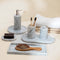 Bathroom set with marble tray, soap dispenser, toothbrush holder, and hairbrush on a neutral background