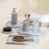Bathroom set with marble tray, soap dispenser, toothbrush holder, and hairbrush on a neutral background