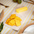 Butter and crackers on a striped tablecloth with kiwis in the background